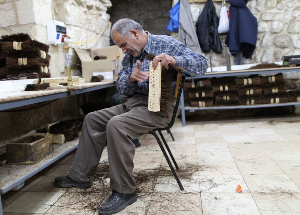 A blind Arab man works on making brooms in a workshop in the Old City of Jerusalem.