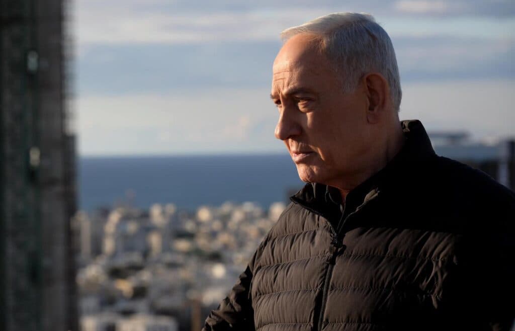 Prime Minister Benjamin Netanyahu looks ahead in an outdoor setting.