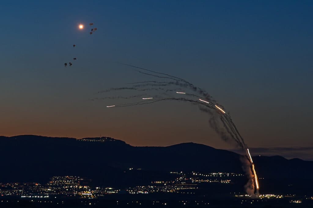 Anti-missile batteries fire interception missiles over northern Israel at night.