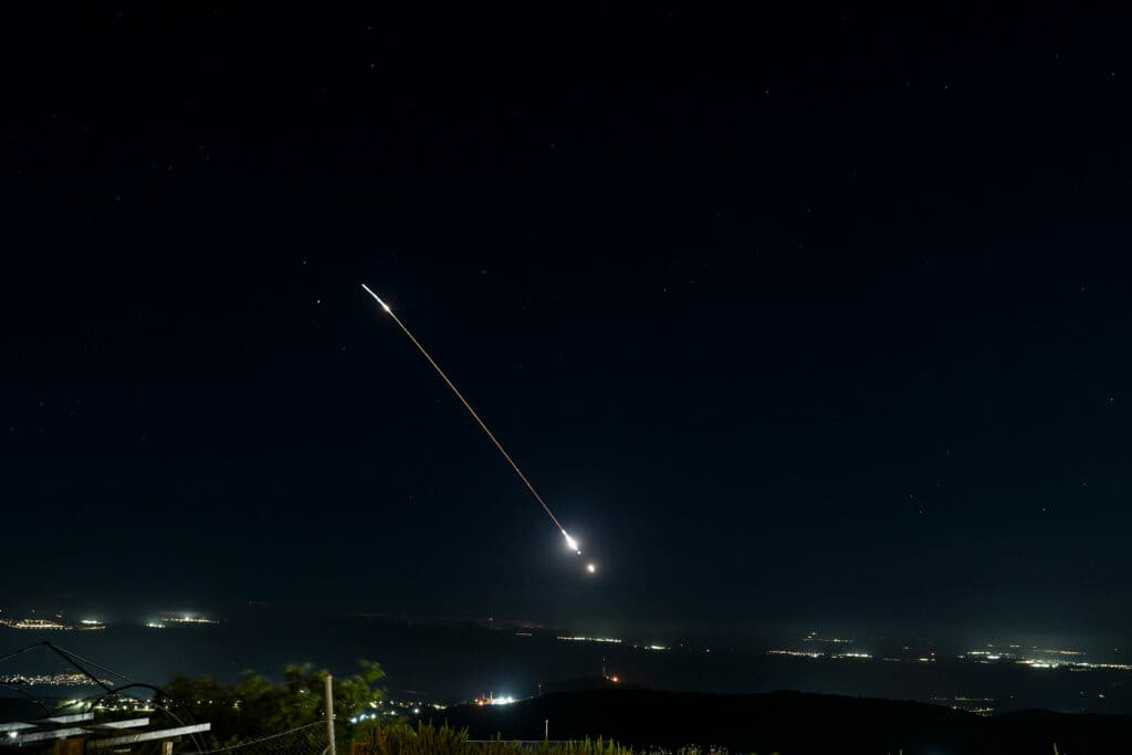 Anti-missile batteries fire interception missiles over northern Israel at night.