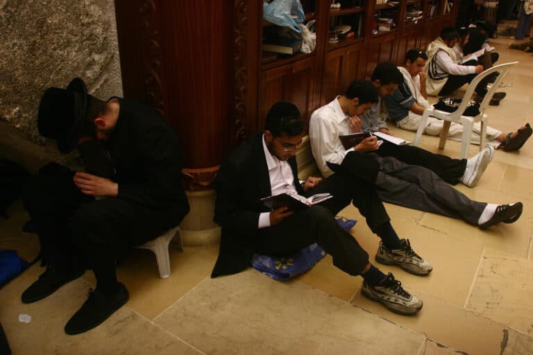 Jews on tisha b'av sitting on floor at western wall
