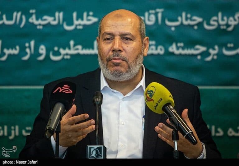 Khalil al-Hayya speaks at a press conference in front of microphones.