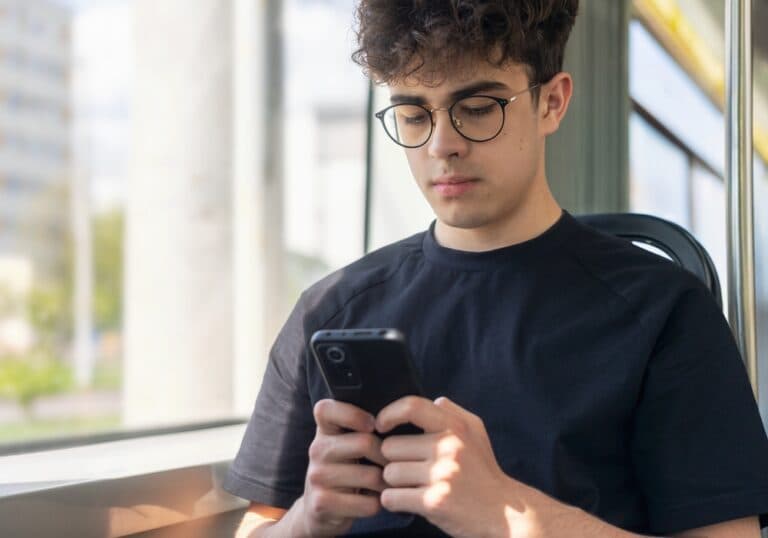 teen boy scrolling phone on bus