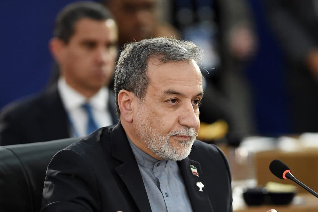Iranian Foreign Minister Abbas Araghchi seated at a meeting with a microphone in front of him.