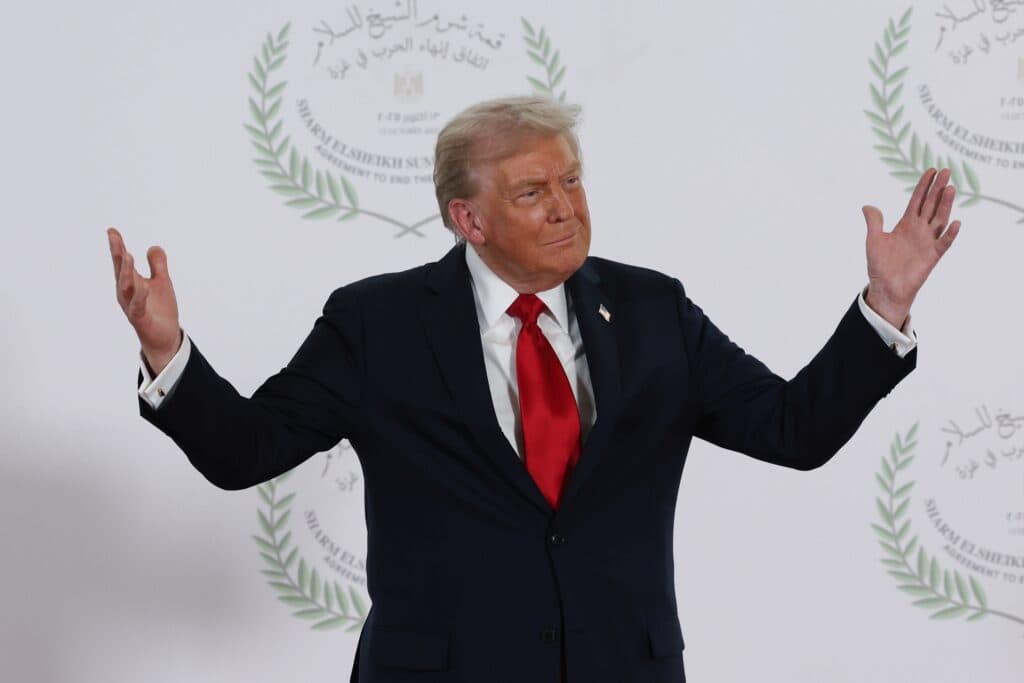 President Donald Trump standing with his arms raised at the Sharm el-Sheikh summit.