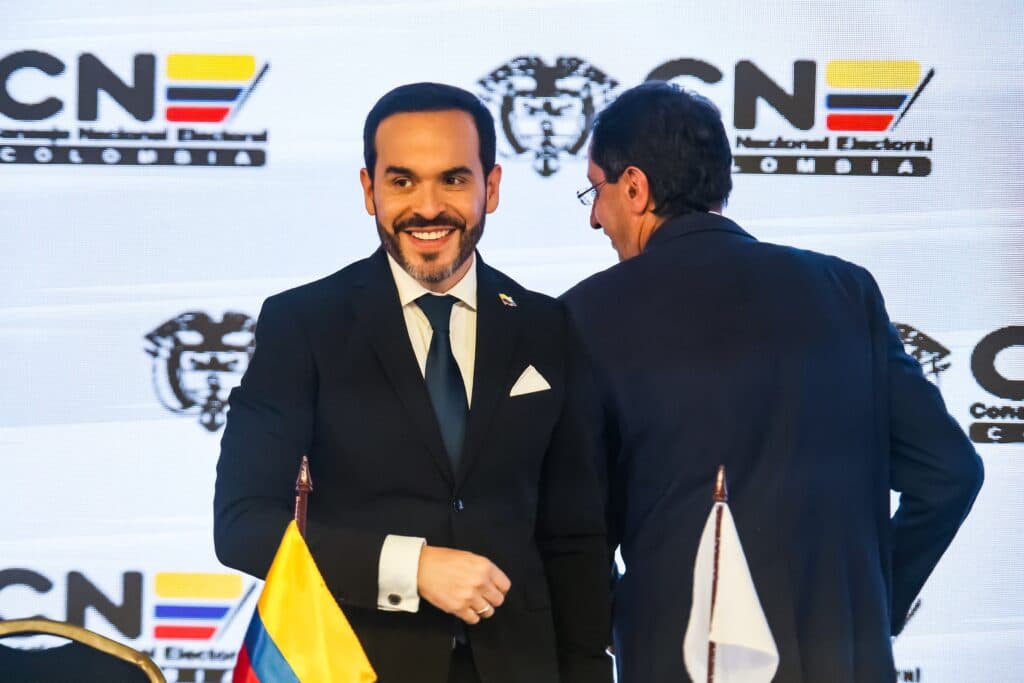 Colombian President Abelardo de la Espriella smiling at a public event with Colombian election symbols behind him.