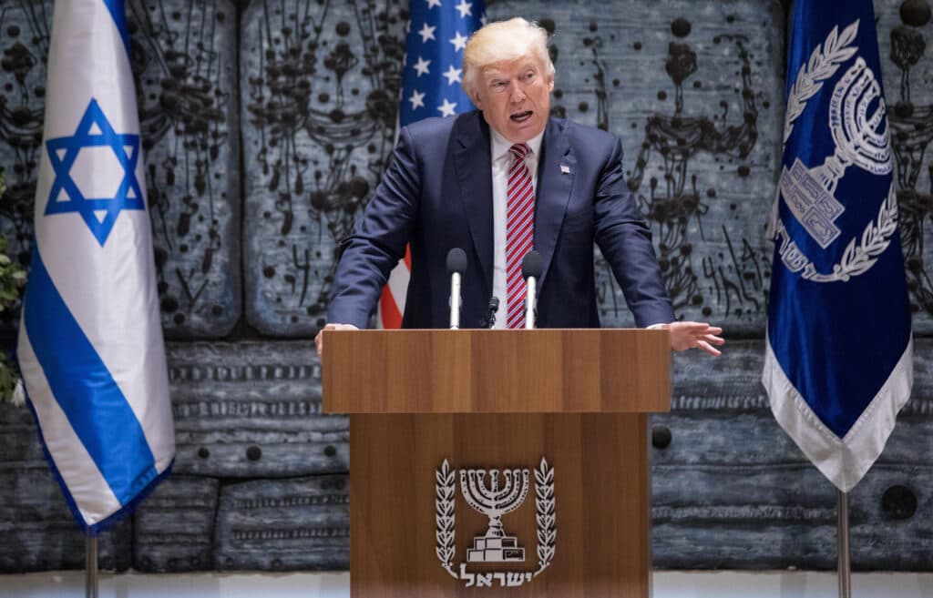 President Donald Trump speaks at a podium in Jerusalem with Israeli and American flags behind him.
