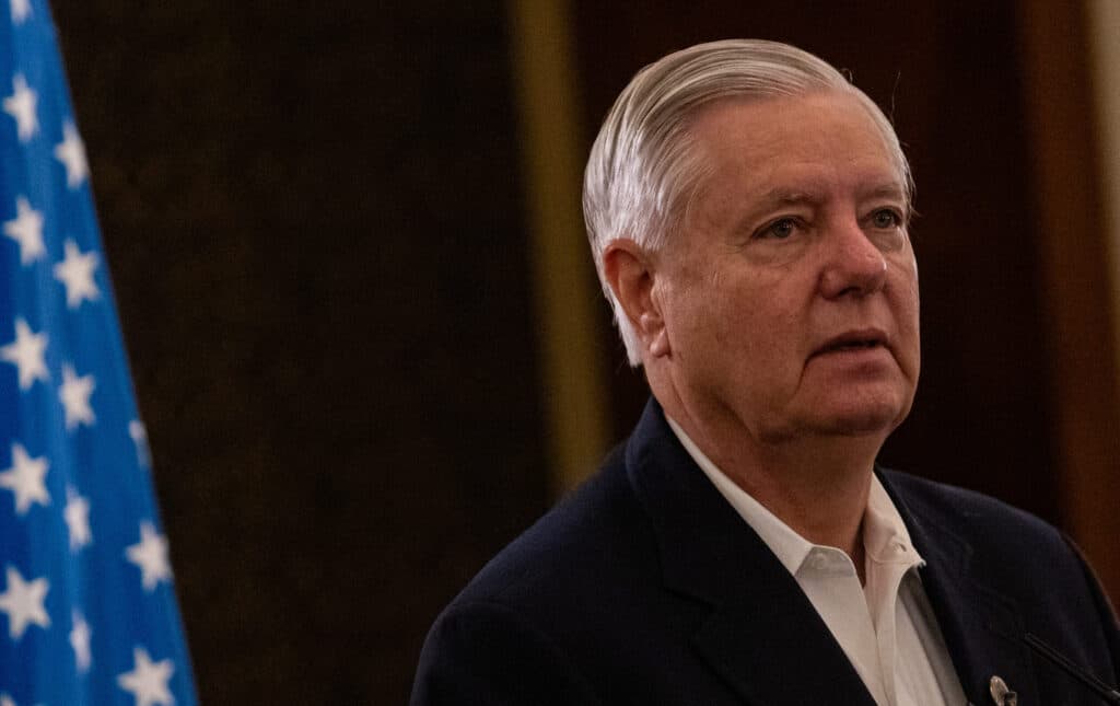 U.S. Senator Lindsey Graham speaks at a press conference in Jerusalem with an American flag behind him.