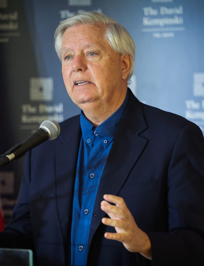U.S. Senator Lindsey Graham speaks at a podium in Tel Aviv with an American flag behind him.