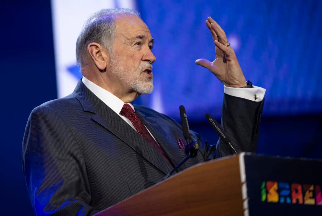 U.S. Ambassador to Israel Mike Huckabee speaking at a podium during the FOZ Ambassadors Summit in Jerusalem.