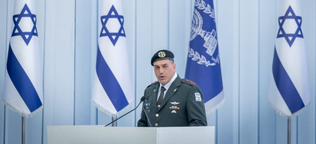 IDF Chief of Staff Eyal Zamir speaks at a podium with Israeli flags behind him.