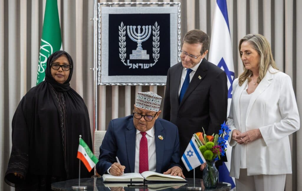 Somaliland President Abdirahman Mohamed Abdullahi Irro signs a guest book beside President Isaac Herzog in Jerusalem.