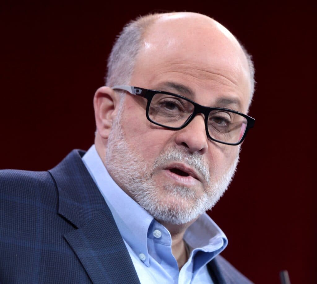 Mark Levin speaking at an event while wearing glasses and a suit.