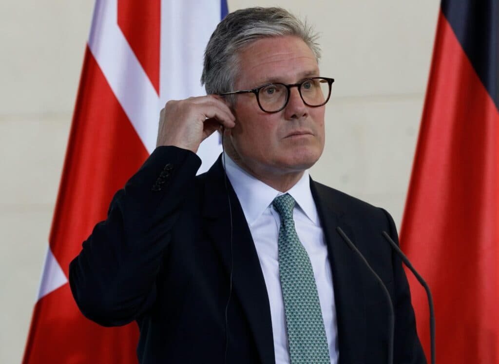 British Prime Minister Keir Starmer standing in front of flags