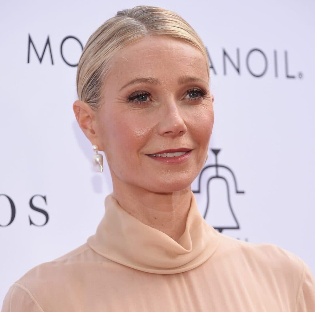 Gwyneth Paltrow at a public event wearing a light-colored dress.