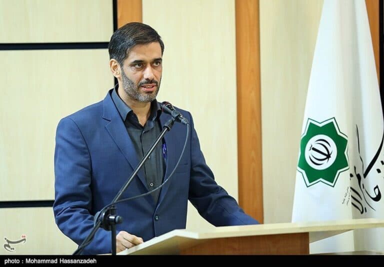 Saeed Mohammad speaks at a podium beside an Iranian institutional flag.