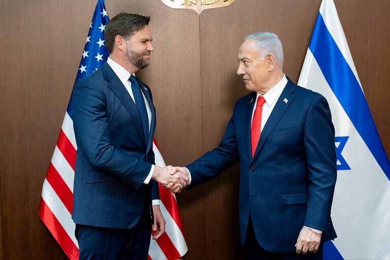Vice President J.D. Vance shakes hands with Prime Minister Benjamin Netanyahu beside American and Israeli flags.