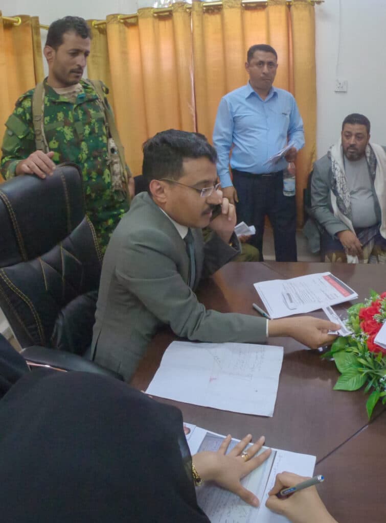 Yemeni officials and security personnel gather around a desk in a government office.