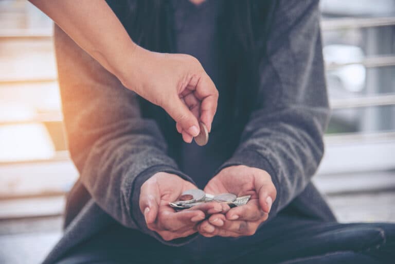 open arms of homeless person receiving charity money from giver