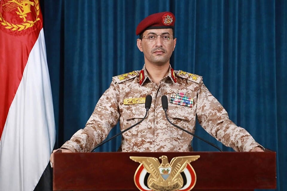 Houthi military spokesman Yahya Saree speaks at a podium in military uniform.