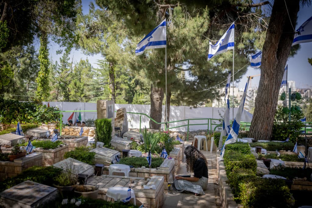 Graves of Israeli soldiers at Mount Herzl Military Cemetery in Jerusalem with Israeli flags placed throughout the cemetery.